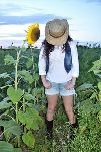 Midsection of woman wearing hat on field against sky