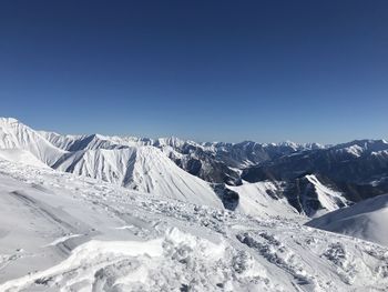 Scenic view of snowcapped mountains against clear blue sky