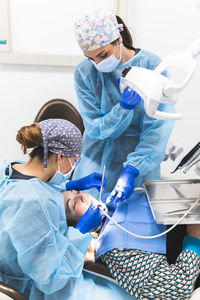 Dentist and assistant with equipment examining patient at clinic