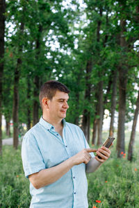 Young man looking at camera while standing on tree