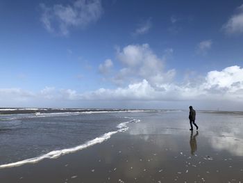 Man walking on beach against sky