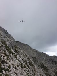 Low angle view of airplane flying over mountains against sky