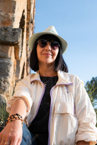 Portrait of young woman standing against wall