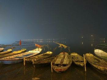 Boats moored at illuminated shore against clear sky at night