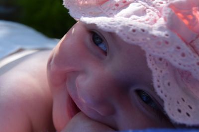 Close-up of shirtless baby girl smiling while lying outdoors