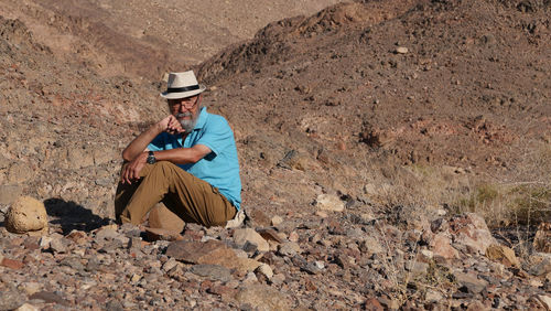 Senior man sitting on rock in the desert 