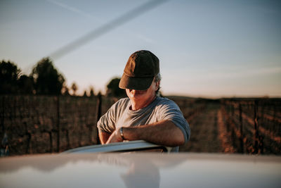 Man with covered face against sky during sunset