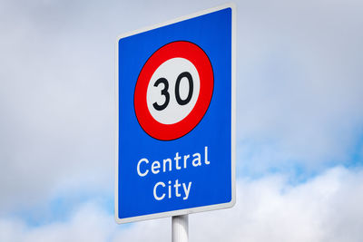 Low angle view of road sign against blue sky