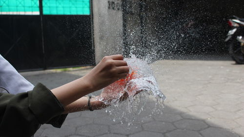 Midsection of men bursting water balloon