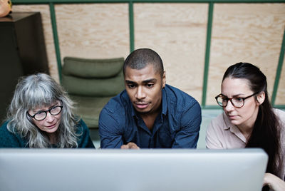 High angle view of male and female colleagues looking at desktop computer in office