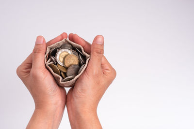 Close-up of hand holding ring against white background