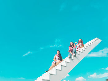 Low angle view of people standing against blue sky