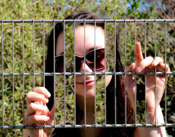 Close-up of hand holding metal fence