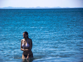 Young woman standing against sea