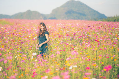 Portrait of smiling woman standing amidst blooming flowers