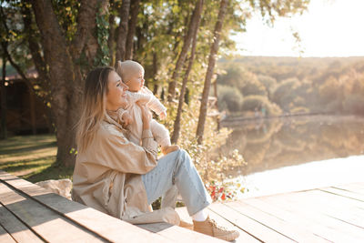 Smiling young mother playing with baby boy 1 year old wear casual clothes over nature background