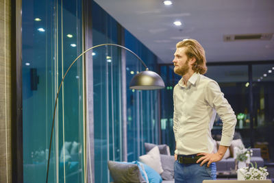 Businessman looking through window while standing in office