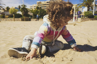 Portrait of girl playing with sand on beach