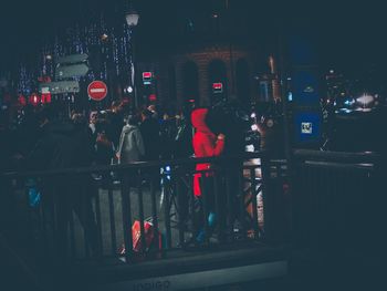 People walking on illuminated street in city at night