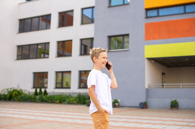 A boy is standing on the street with a phone