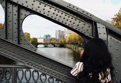 Rear view of woman on bridge over river in city
