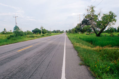 Road by trees against sky