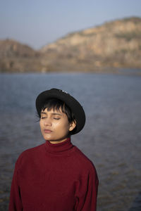 Portrait of an aesthetic looking girl wearing red sweater or sweatshirt with a black hat captured.