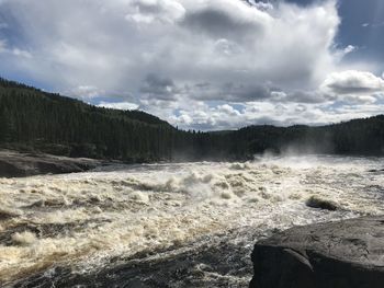 Scenic view of waterfall against sky