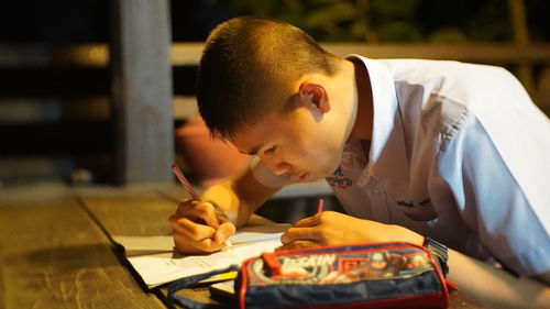 Teenager boy writing on table