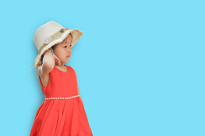 Woman looking away while standing against blue background
