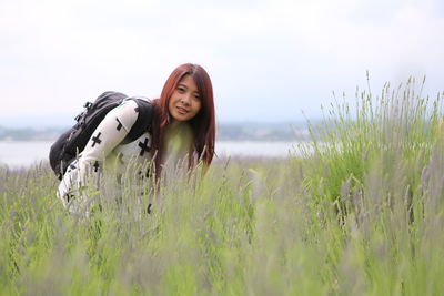 Young woman smiling on field against sky