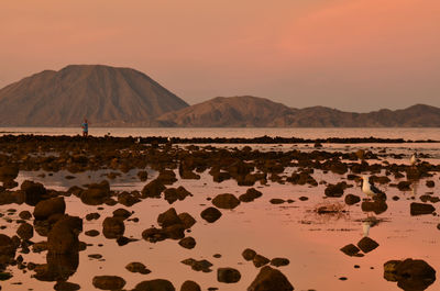 Scenic view of sea against mountains during sunset