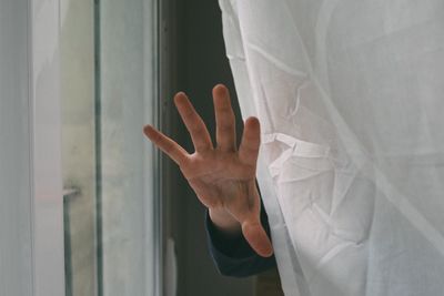 Close-up of human hand against curtain