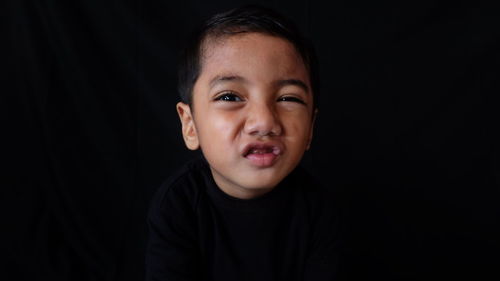 Portrait of boy against black background