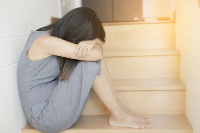 Midsection of woman sitting on floor at home