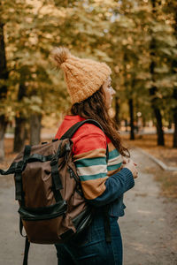 Rear view of woman wearing hat standing against trees during winter