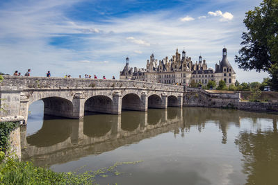 Arch bridge over river against cloudy sky