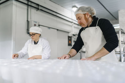 Male and female chefs working in cheese factory