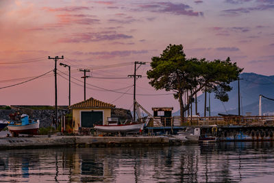 Boats moored at harbor against sky during sunset