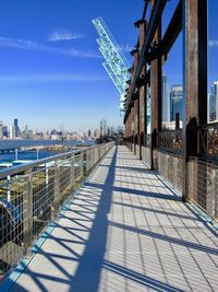 Footpath amidst buildings against sky on sunny day