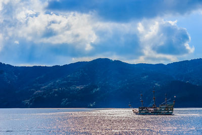 Scenic view of sea by mountains against sky