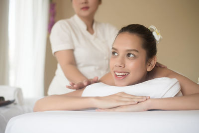 Smiling young woman being massaged on table in spa