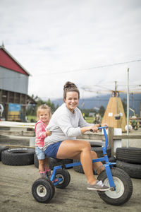 Mother and daughter riding on tricycle on racetrack.