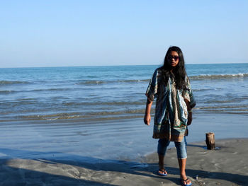 Full length of woman standing on beach against sky