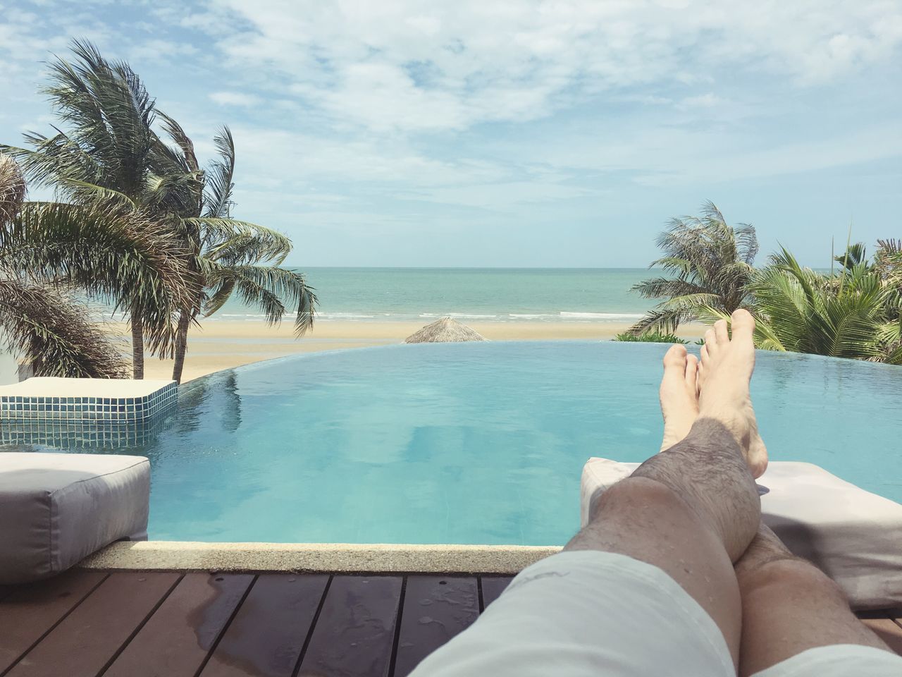 sea, water, sky, horizon over water, beach, low section, leisure activity, relaxation, lifestyles, cloud - sky, tree, swimming pool, shore, personal perspective, vacations, person, barefoot