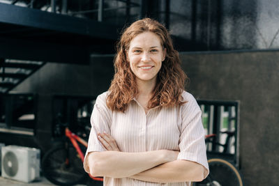 Portrait of young woman standing against wall