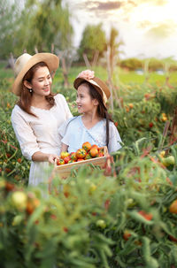 Smiling young woman looking away against plants on field