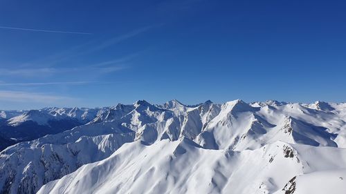 Scenic view of snowcapped mountains against blue sky