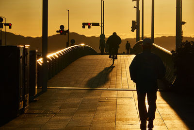 Rear view of silhouette people walking on footpath in the morning