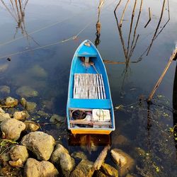 High angle view of boat hanging on rock by lake